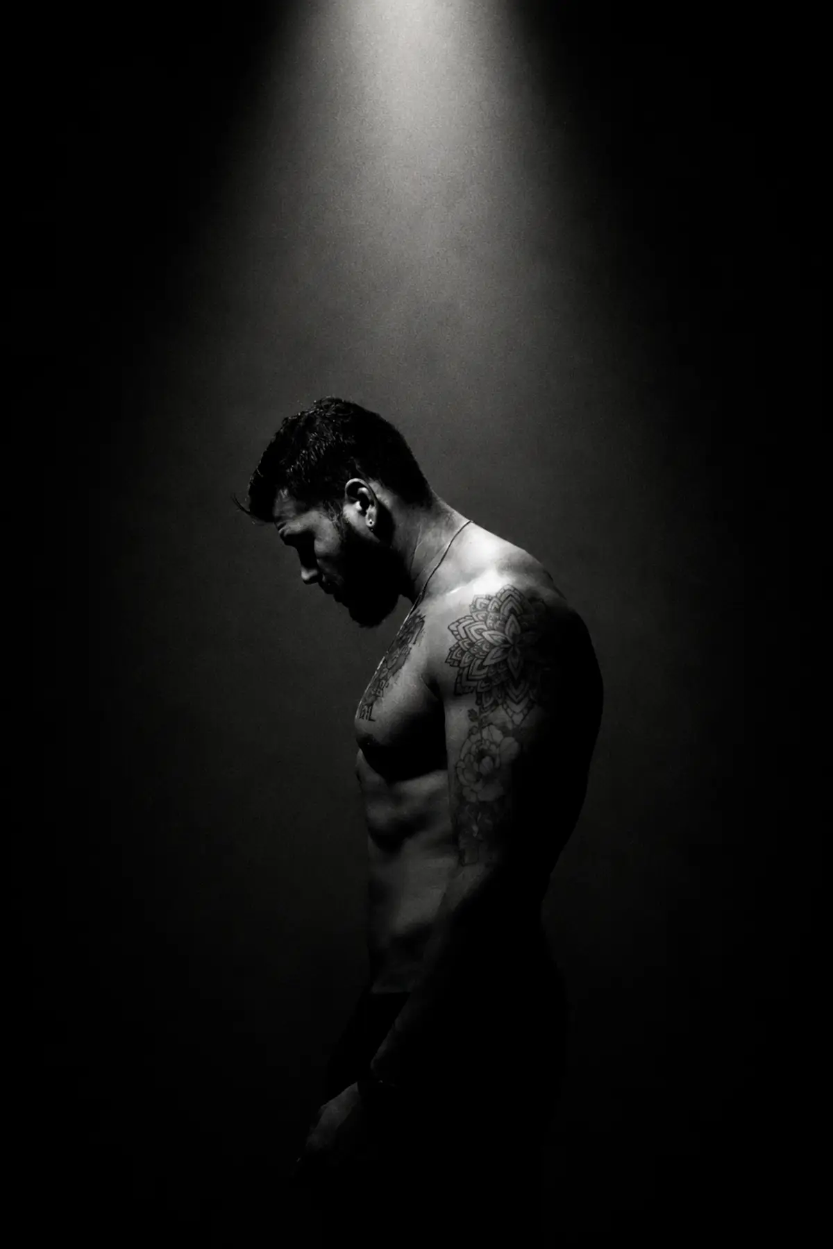 A man standing quietly under a single overhead light